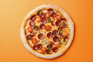 Pizza with smoked sausage, cherry tomatoes, dried chilli, jalapeno peppers and mozzarella. Orange background. Top view. Copy space