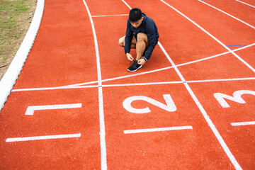 Hands man runners tie shoelaces prepared to run on track. Young asian man wearing sportswear running sport stadium.Training athlete work out at outdoor concept.