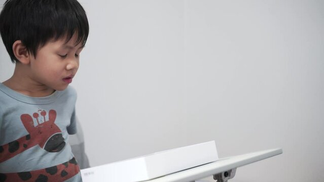 Asian boy about 4 years old using computer tablet in a box with happy smile as self study at home