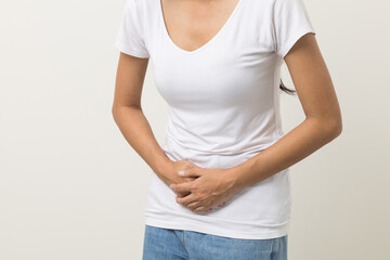 A woman had a stomach ache and gastritis. She put her hand on her stomach and squeezed it to relax and soothe. She is 25 years old and has menstrual cramps. Shot on isolated white background.