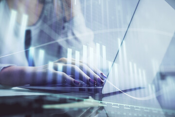 Double exposure of woman hands typing on computer and financial graph hologram drawing. Stock...