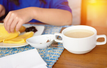 Cup or bowl of soup on blur plate with crape and jam and hand while eating breakfast