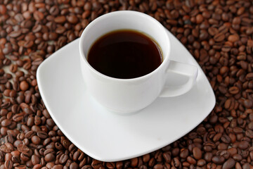 White cup of coffee close up on coffee beand background