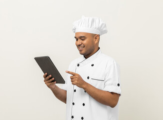 Young asian male chef holding digital tablet thinking to choose various delicious dish menu good taste for customer order. Online delivery food buying variety of dish