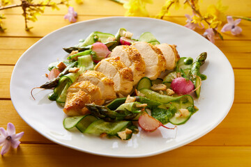 Plate with chicken breast and salad on wooden table