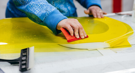 Applying colored yellow membrane to a surface of plastic 3d letter of signboard. Worker's hands...