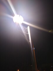 Fototapeta na wymiar Cobweb on top of a lamppost between three lanterns at night