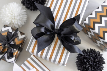 Gift boxes wrapped in Striped and chevron geometric paper with black ribbon bows close up