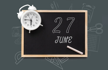 june 27. 27th day of month, calendar date.   Blackboard with piece of chalk and white alarm clock on green background. Concept of day of year, time planner, summer month