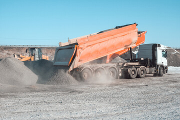 trucks carry and unload crushed stone at an asphalt concrete plant, which is needed for road...
