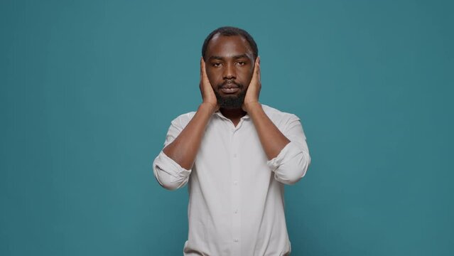 African american man doing three wise monkeys symbol, covering eyes, mouth and ears to keep secret and not find out confidential information. Young person respecting privacy and secrecy.