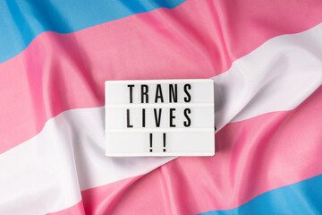 sign with Lgtbiqsign with message trans lives on pink white and blue trans flag message on rainbow...