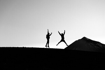 Silhouettes of people jumping against the backdrop of the Teide volcano