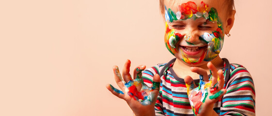 Humorous portrait of cute cheerful child girl showing her hands and face painted in bright colors....