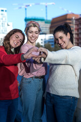 three female friends making heart shape from hand