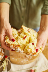 Woman hand cut Easter cake on wooden rustic table.
