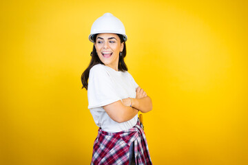 Young caucasian woman wearing hardhat and builder clothes over isolated yellow background looking...