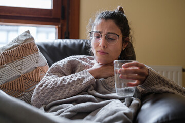 Woman with sore throat drinking water.