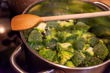 brocolli in a pot in the kitchen with a wooden cooking spoon