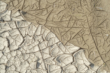 Dried and wet cracked silt soil, separated on diagonal, textured.