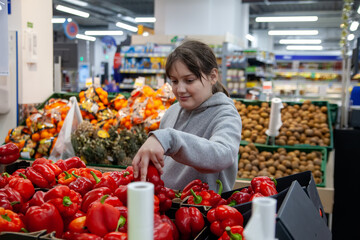 Young positive teen girl consumer  at grocery section of supermarket