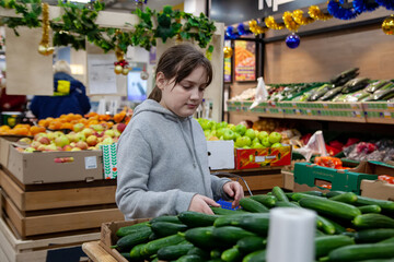 Young positive teen girl consumer  at grocery section of supermarket