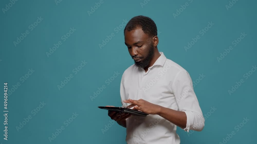 Poster company worker browsing internet on digital tablet in studio, working on internet website to plan su