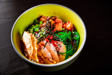 Fresh seafood recipe. Shrimp salmon poke in bowl on black wooden table background