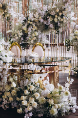 Wedding. Banquet. The festive table is decorated with compositions of white flowers and greenery. There are plates, glasses, candles and cutlery on the table.