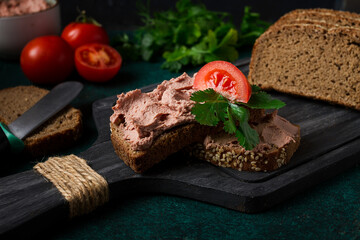 Liver meat pate spread on rye bread, breakfast, close-up, dark background. no people, selective focus,