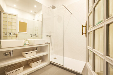 Bathroom with glass-enclosed shower stall with white wicker baskets, brick cabinet, wooden door...