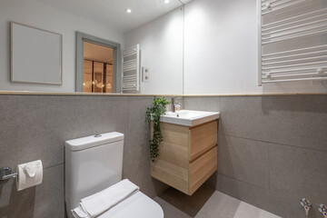 Bathroom with porcelain hanging sink on wooden cabinet, integrated wall-to-wall mirror, white heated towel rail