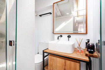 Bathroom with white porcelain sink on wooden cabinet and mirror with matching frame