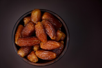 Clay cup full of ripe dried dates top view. Copy space .