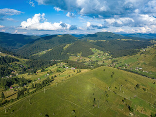 Green mountains of Ukrainian Carpathians in summer. Sunny day, rare clouds. Aerial drone view.