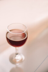 Original still life with a glass of red wine on a background in peach tones