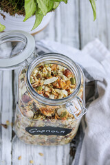 Bale glass jar container with swing top lid open full of vegan keto Granola made with pecans, hazelnuts, unsweetened coconut, sunflower seeds, pepita seeds and sweetened with erythritol. Top view.