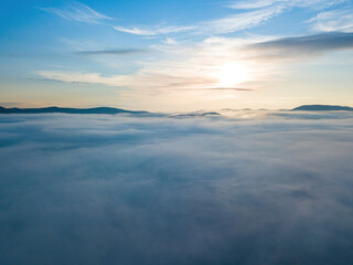 Fototapeta na wymiar The rays of dawn over the fog in the Ukrainian Carpathians. Aerial drone view.