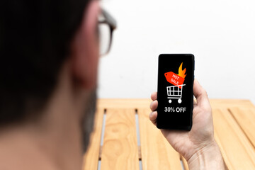 Person looking at the screen of a smartphone that announces a 30 percent discount for the hot sale.