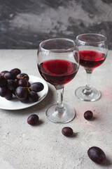 two glasses with red wine and grapes on a concrete background