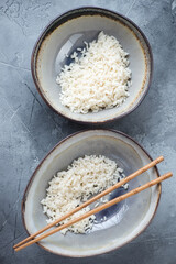 Above view of two bowls with steamed rice on a grey concrete background, vertical shot