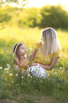 Mother and her little daughter are having fun in a summer meadow with dandelions. Happy family in summer. Concept of healthy family without allergies. High quality photo