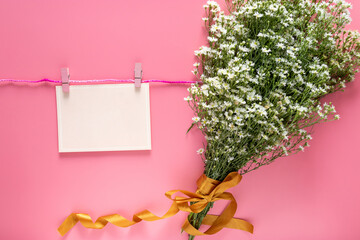 mockup of pastel pink card note blank paper sheet hang on rope with clothes peg and spring fresh...