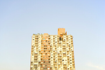 Urban condo, modern flat cosmopolitan residential building structure against pastel blue gradient skyline background.