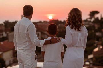 Fototapeta premium Happy family enjoys and spends time together on the roof of the house while watching the sunset on the open sea together