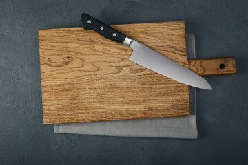 Cutting wooden board and chef knife on the table.