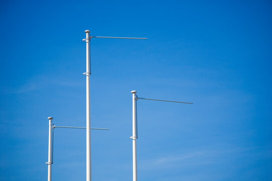 Triple Empty Flagpole Against Blue Sky.