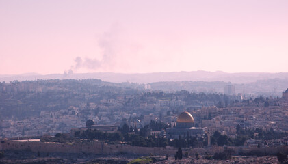A view on n rooftops of Old City of Jerusalem and golden Dome of the Rock from Mount Scopus. Haze. Fire smoke raising at backgrounds.  Retro