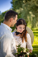 Happy young people in wedding dresses stand in the meadow and look at each other. portrait of a bride looking at a beautiful wedding bouquet