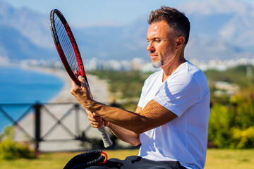 man holding tennis racket outdoors at sunny day